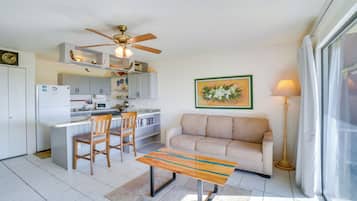 A compact living space with a kitchenette, a sofa, a coffee table, and a ceiling fan.
