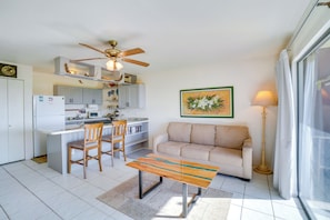A compact living space with a kitchenette, a sofa, a coffee table, and a ceiling fan.
