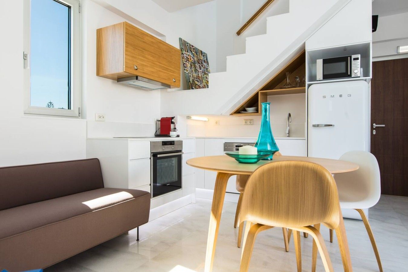 Een moderne keuken met een inbouwoven, een magnetron en een eethoek met een tafel en stoelen.