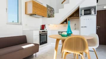 Een moderne keuken met een inbouwoven, een magnetron en een eethoek met een tafel en stoelen.