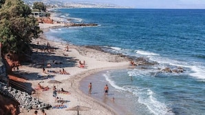 Una playa con aguas cristalinas, sombrillas y gente tomando el sol.