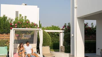 Una piscina con sillas de descanso y una pérgola, rodeada de arquitectura moderna.