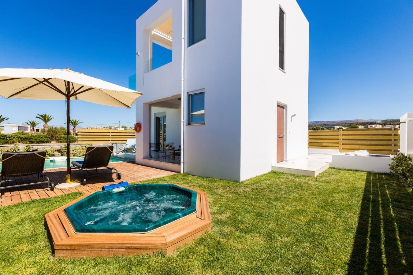 A modern two-story house with a swimming pool, outdoor seating, and a hot tub.
