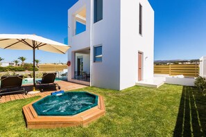 Une maison moderne à deux étages dotée d’une piscine, d’un espace salon extérieur et d’un jacuzzi.