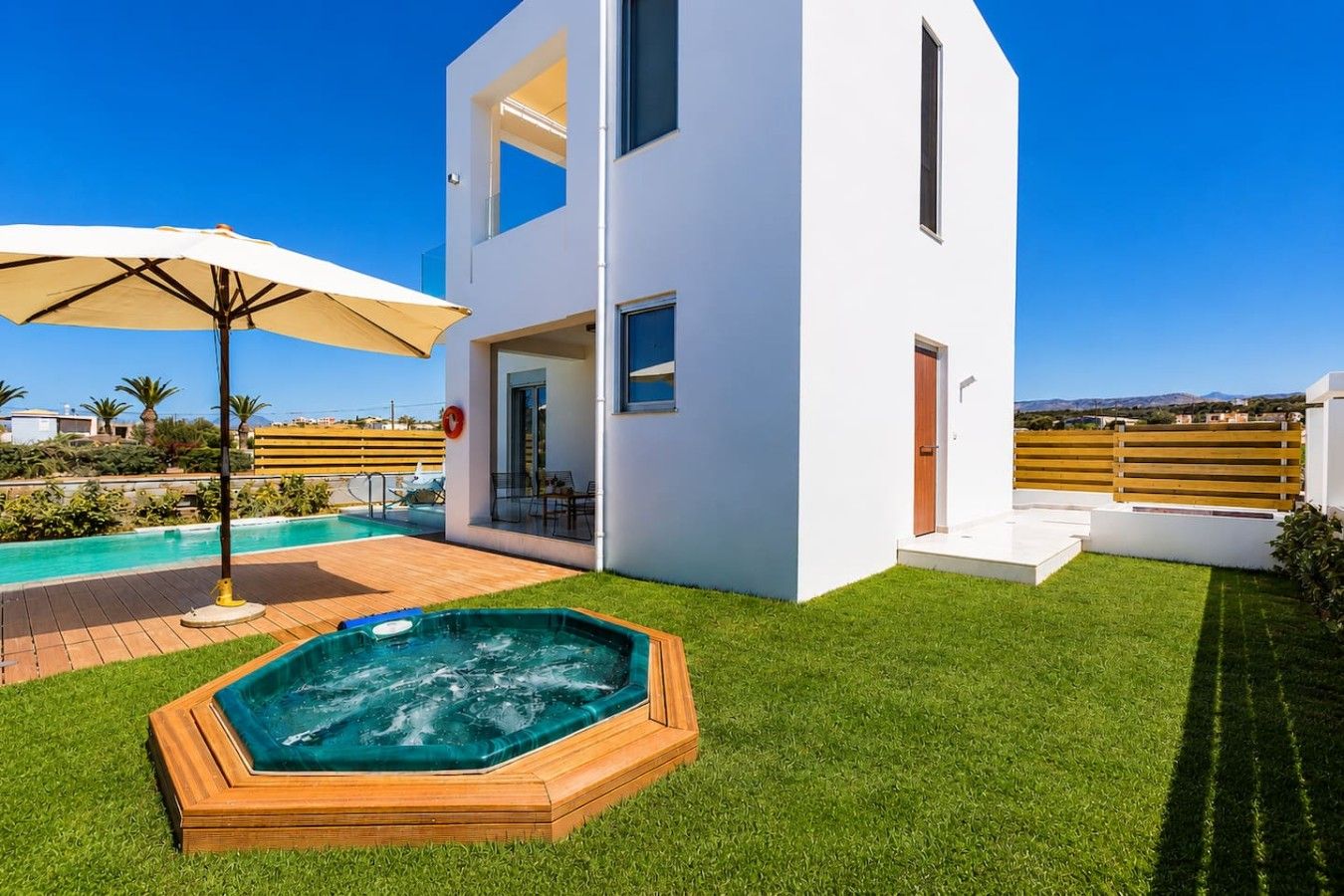 Ein modernes, zweistöckiges Haus mit Swimmingpool, Whirlpool und Terrassenbereich.