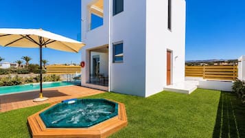 Ein modernes, zweistöckiges Haus mit Swimmingpool, Whirlpool und Terrassenbereich.