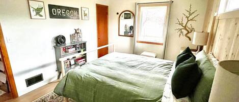 A bedroom with a bed, a bookshelf, a mirror, and a window.