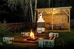 A wooden outdoor barbecue area with a fire pit, a covered seating area, and a chimney. - In The Woods Lodge With hot tub Inside Puszcza Knyszyśnka - Two-bedroom Villa (Suprasl)