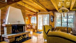 A cozy cabin interior with a fireplace, wooden floors, a dining area, and a comfortable seating area. - In The Woods Lodge With hot tub Inside Puszcza Knyszyśnka - Two-bedroom Villa (Suprasl)
