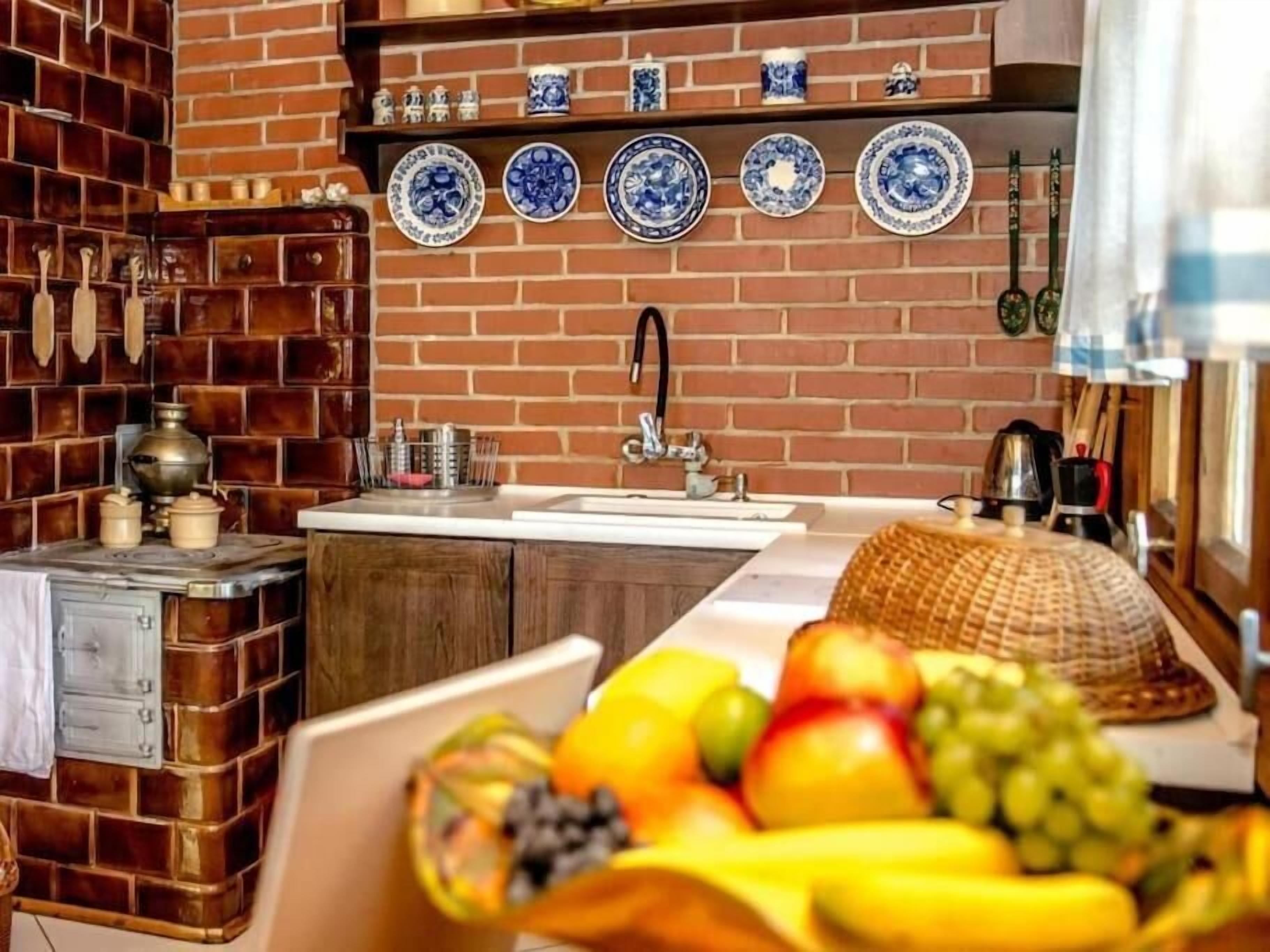 A kitchen with a brick wall, a sink, and a fruit bowl on the counter.