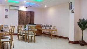 Un espace repas avec des chaises et des tables en bois, un buffet et une plante en pot.