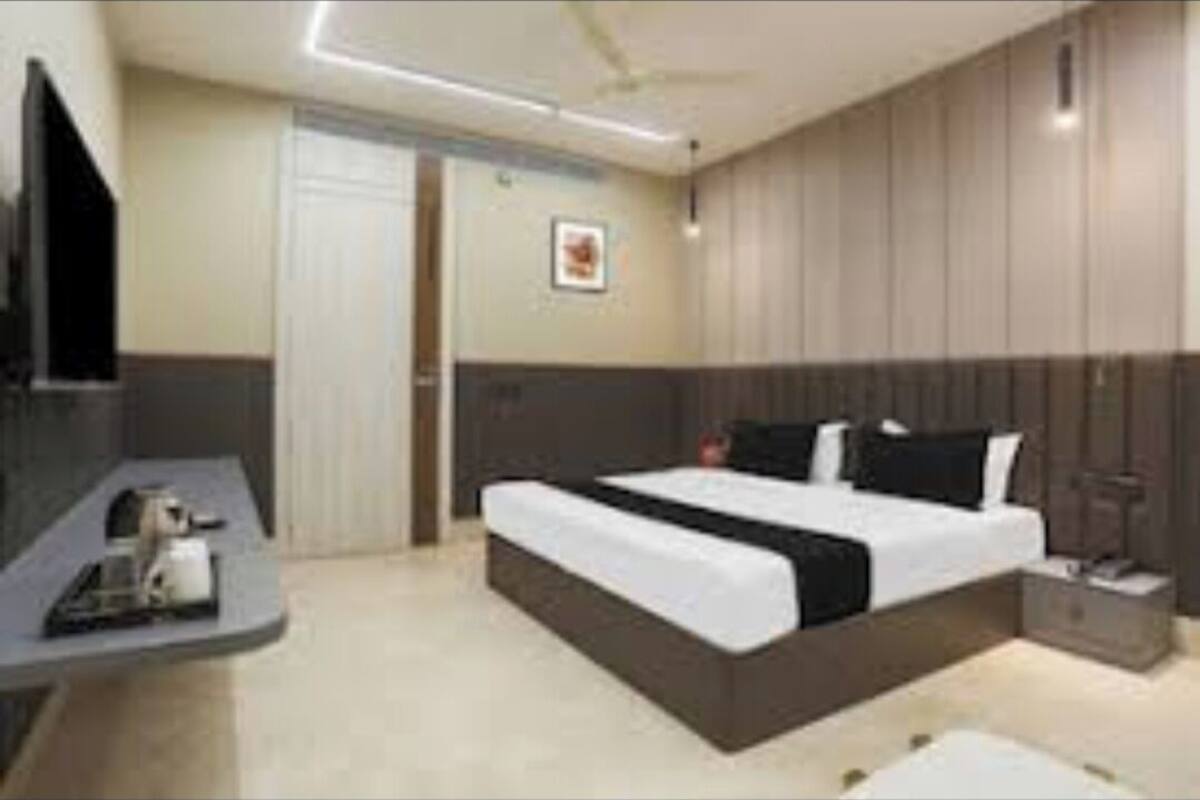 Una habitación de hotel moderna con una cama grande, una mesita de noche, un televisor y un armario.