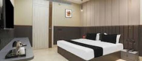 A modern hotel room with a large bed, a bedside table, a TV, and a wardrobe.