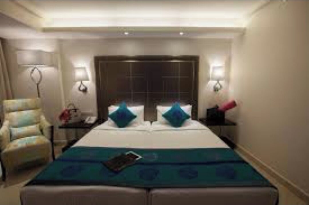 A hotel room with a large bed, two bedside tables, a chair, and a nightstand.