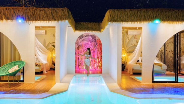 Un complexe hôtelier de luxe doté d’une piscine centrale, de chambres privées aux toits de chaume et d’un ciel étoilé visible à travers le plafond.