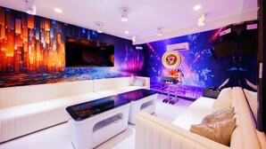 Un salon moderne doté d’un grand téléviseur à écran plat, d’un canapé, d’une table basse et d’un mur orné d’un motif abstrait aux couleurs vives.