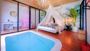 Une chambre avec une grande piscine, un lit à baldaquin et un bureau avec un miroir.