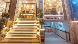 Fachada del hotel Majestik Villa con señalización iluminada, una escalera que conduce a la entrada y plantas en macetas en la base.