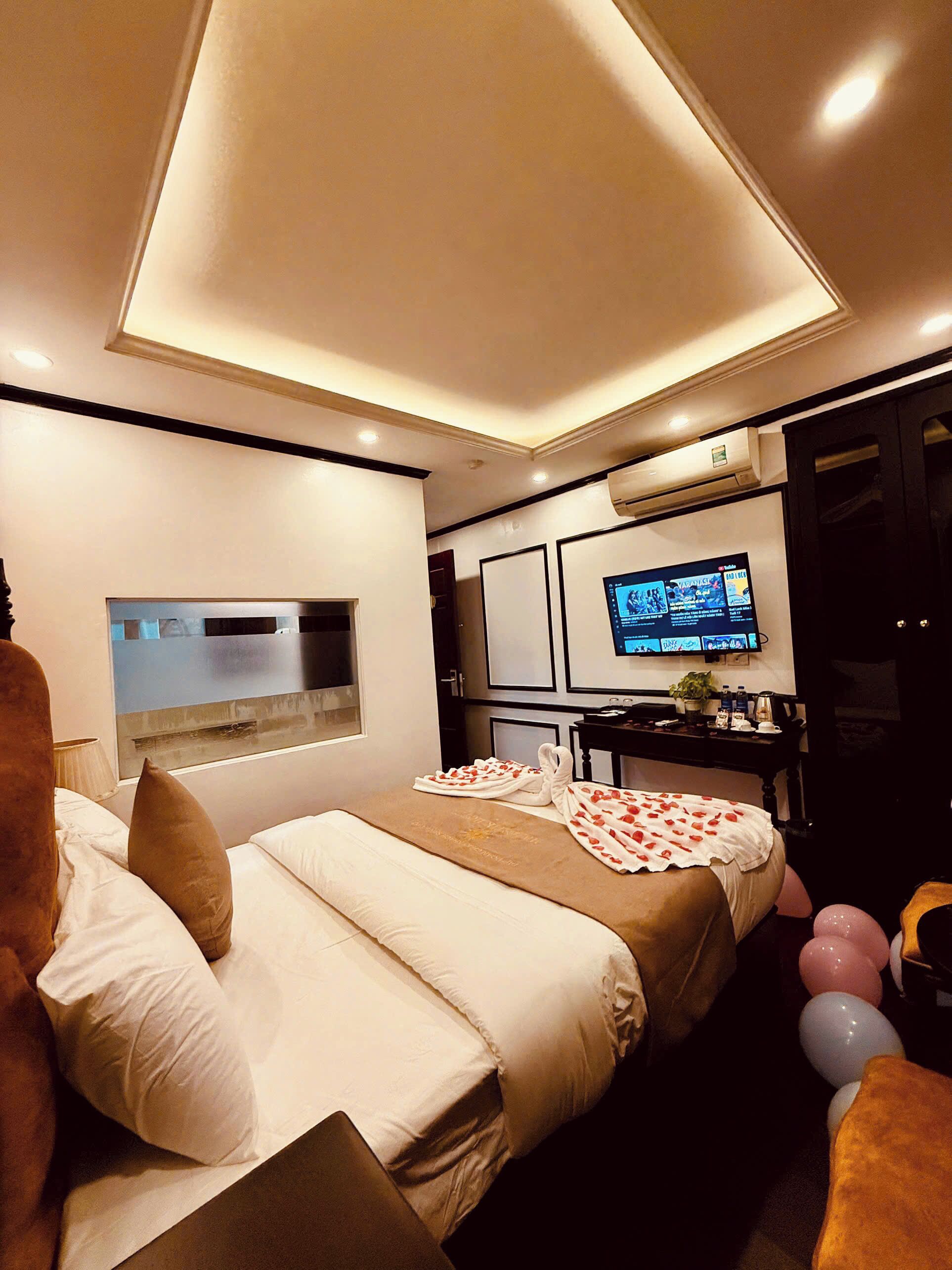 A modern hotel room with a large bed, a desk with a computer, and a TV on the wall.