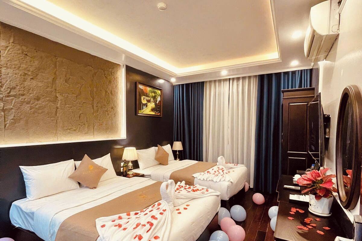 A hotel room with two beds, a desk, and a mirror.