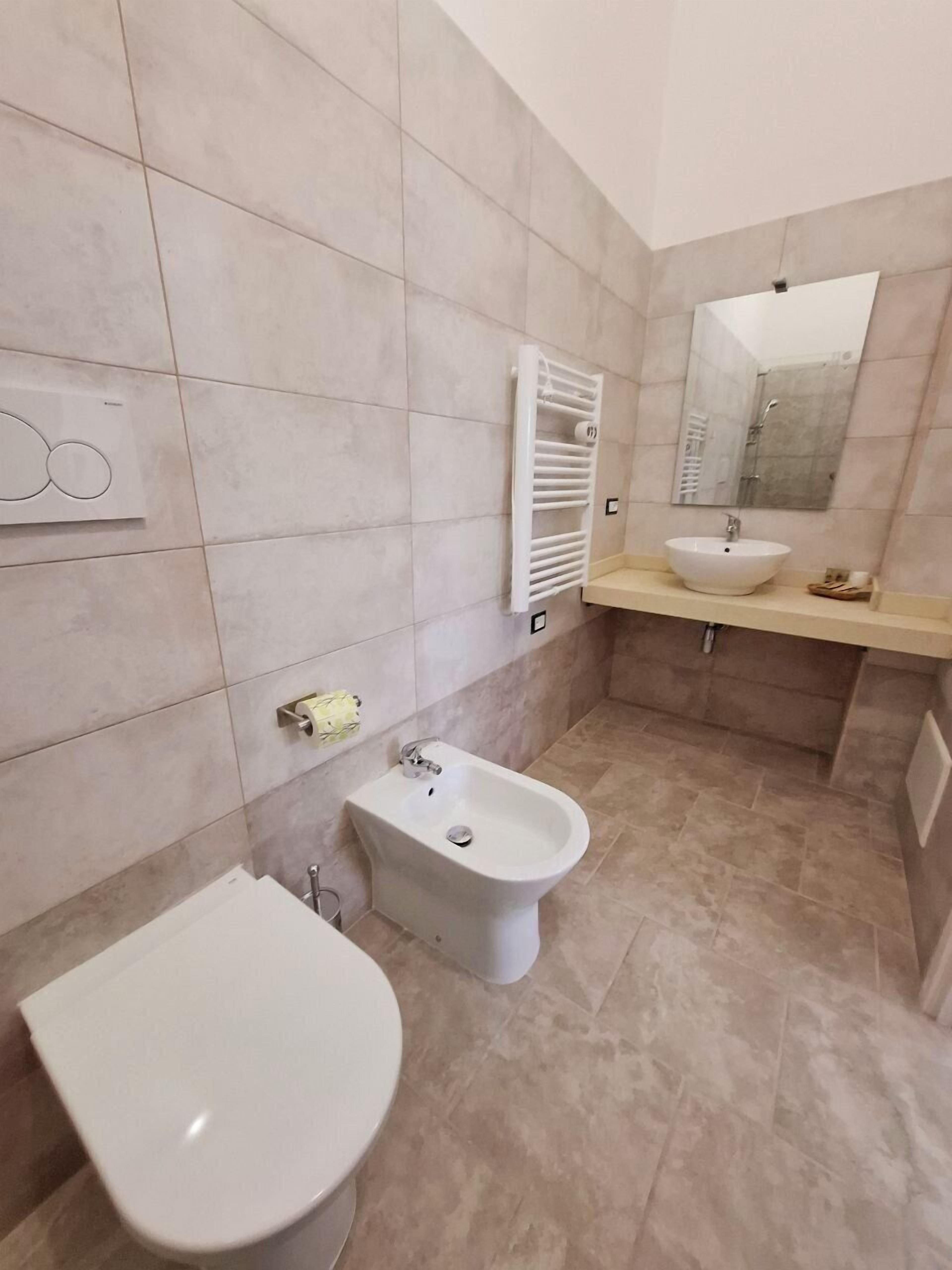 Une salle de bain moderne équipée d’un bidet, d’un lavabo et d’un miroir.