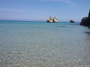 A clear beach with rocky formations in the water. - Tenute Masseria Notari (Borgagne)