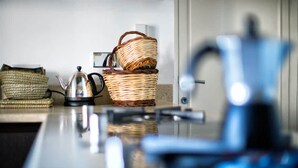 A kitchen counter with a kettle, a basket, and a woven bag.