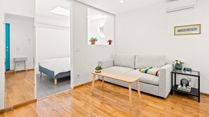 A modern, minimalist room with a sofa, a small table, and a bed. - Scenic Retreat With Deck Stunning Views in LA (Glendale)
