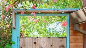 A wooden gate with a decorative metal ornament and a small bell, set within a turquoise frame. - Scenic Retreat With Deck Stunning Views in LA (Glendale)
