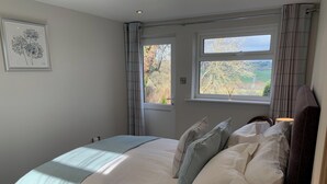 Une chambre à coucher avec un lit, une table de chevet, une lampe et une fenêtre avec des rideaux.