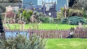 Une maison à deux étages avec une cour clôturée, entourée d’une végétation luxuriante.