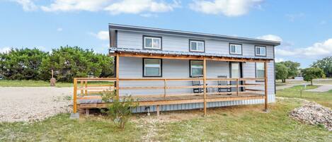 A two-story house with a wooden deck and a covered porch.
