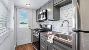 A compact kitchen with a stove, microwave, and refrigerator.