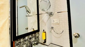 Ein Badezimmer mit einem weißen Waschbecken, zwei Spiegeln, einem Handtuchhalter und einer Seifenspender.