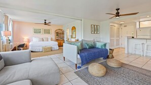 A spacious room with a large bed, a sofa, a small table, and a kitchenette.