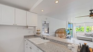 A modern kitchen with granite countertops, white cabinetry, and a built-in dishwasher.
