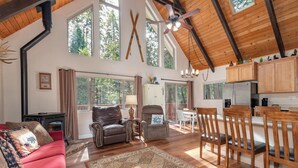 A spacious living room with a red sofa, a patterned rug, and a wooden dining area with chairs.