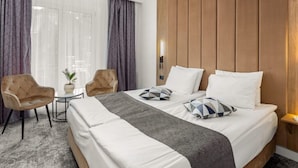 A hotel room with a large bed, two armchairs, a small table, and a potted plant. - Hotel Soimul (Brasov)