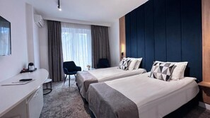 A hotel room with two beds, a desk, a chair, and a large window with curtains. - Hotel Soimul (Brasov)