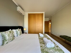Une chambre d’hôtel comprenant un lit, une table de chevet avec une lampe, une armoire en bois et un banc.