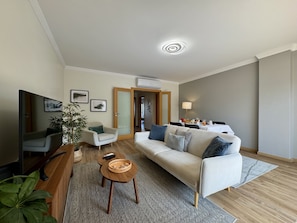 Un salon moderne avec un canapé, un fauteuil, une table basse et un téléviseur.