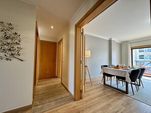 Camera d'albergo con zona pranzo, pavimento in legno, una lampada e vista esterna.
