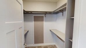 A walk-in closet with a central door, shelving units, and a hanging rod.
