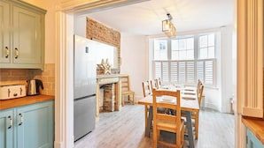 Une cuisine équipée d’un réfrigérateur, d’une cuisinière et d’une table à manger en bois avec des chaises.