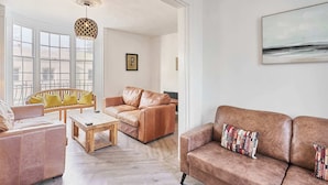 Un salon avec une table basse en bois, deux canapés en cuir, un banc jaune et une suspension.