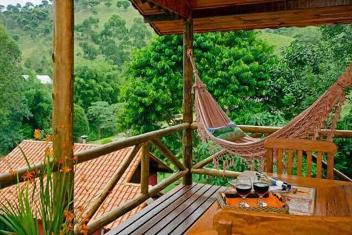 A wooden deck with a hammock and a table set for two, overlooking a lush green landscape.
