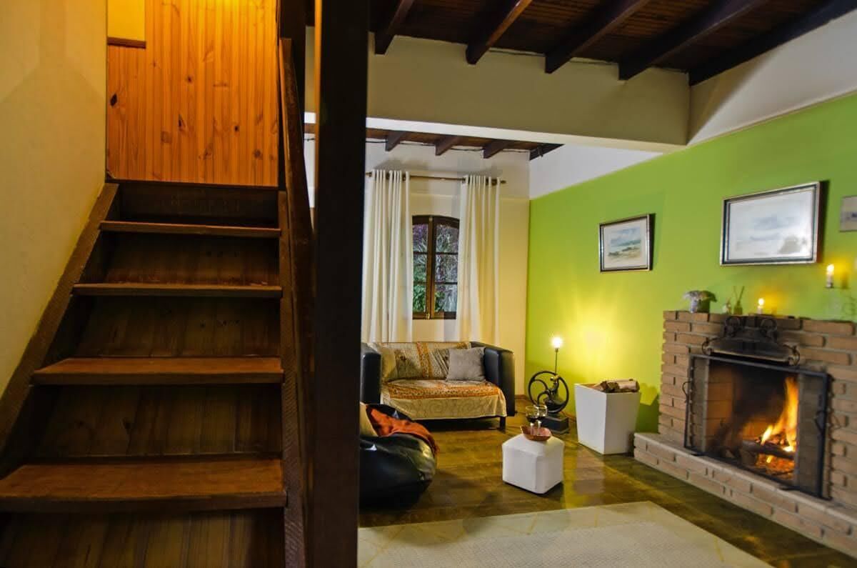 A staircase leading to a living room with a fireplace, a sofa, and a window with curtains.