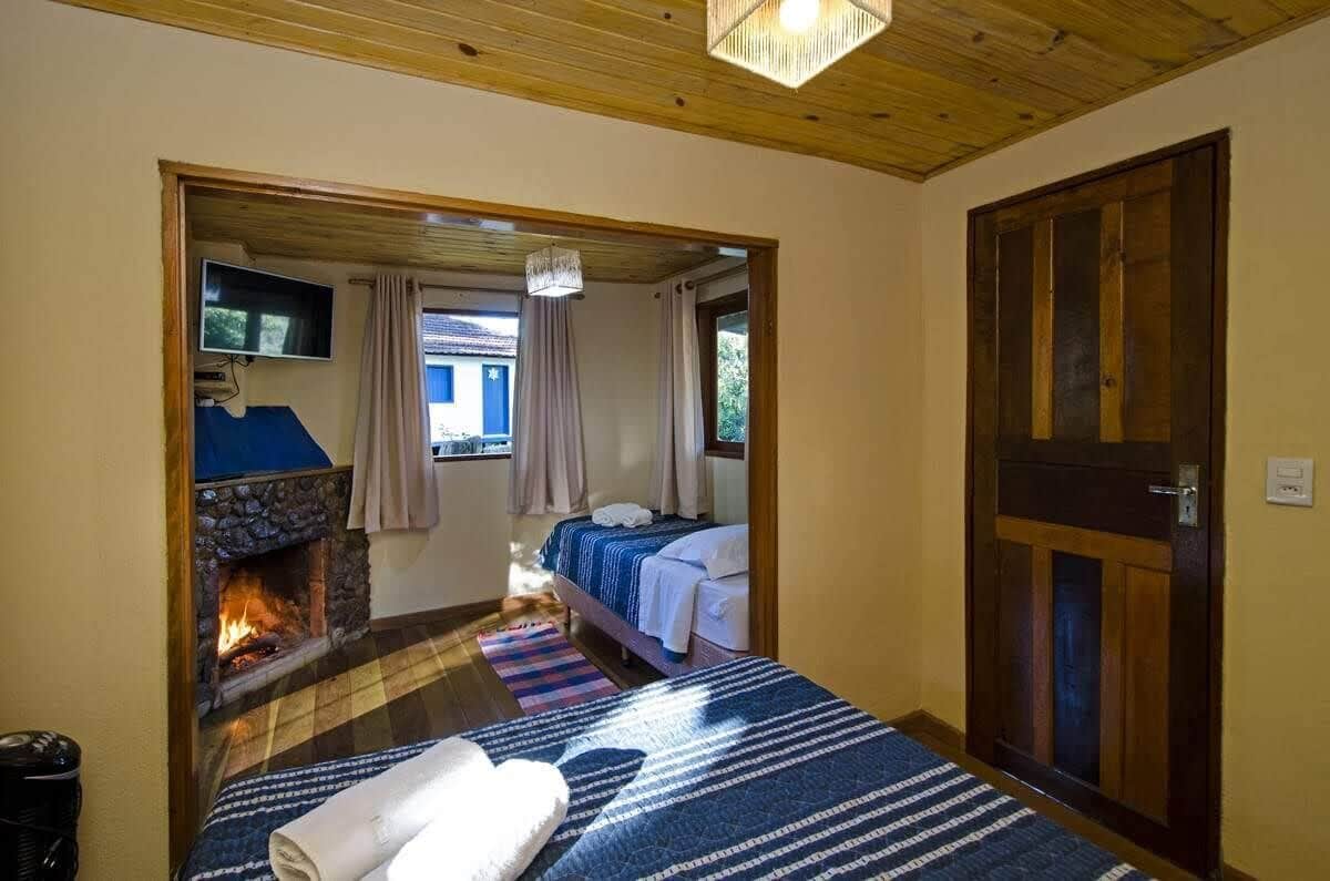 A cozy room with a fireplace, a bed with a blue and white striped bedspread, and a wooden door.