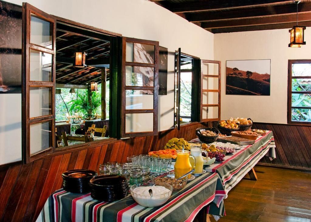 A buffet table with various food items and drinks, wooden walls, and a view of greenery outside.