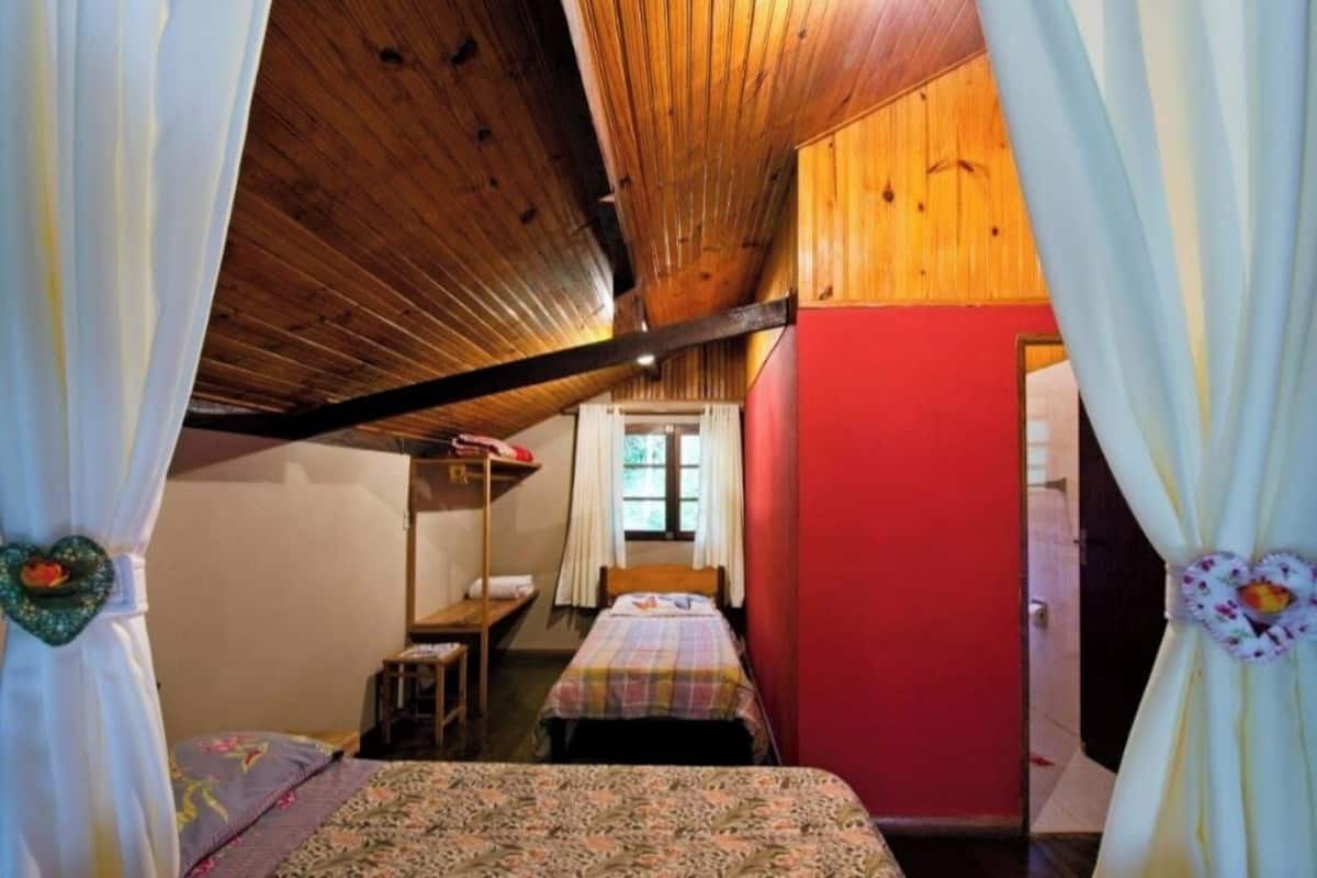 A cozy bedroom with a bunk bed, a single bed, and a window with curtains.
